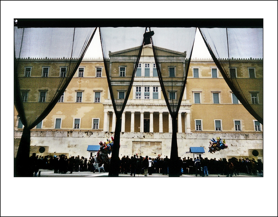 Φωτογραφία της πρόσοψης Βουλής των Ελλήνων, με κόσμο να παρακολουθεί την αλλαγή φρουράς στο μνημείο του αγνώστου στρατιώτη, πίσω από μαύρες κουρτίνες